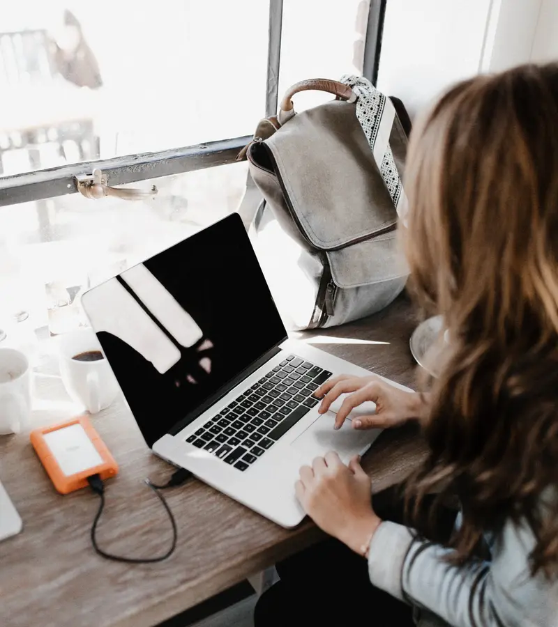 Someone working at a laptop by a window